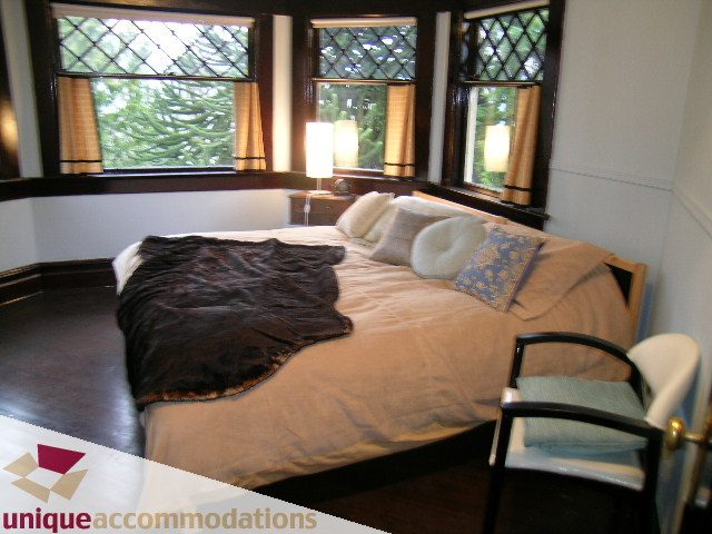 Bright bedroom with large windows, cozy bedding, and hardwood floors. - PH - 2812 Yukon St, Vancouver West Side