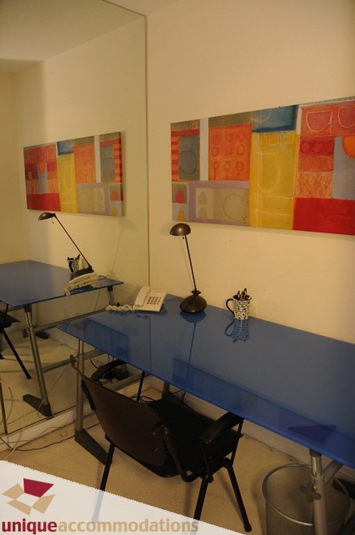 Modern office space with vibrant artwork, blue desk, and sleek desk lamp. - 3101 - 1328 W. Pender Street, Vancouver Downtown
