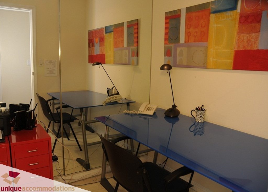 Modern office space with blue desks, colorful abstract art, and a red storage unit. - 3101 - 1328 W. Pender Street, Vancouver Downtown