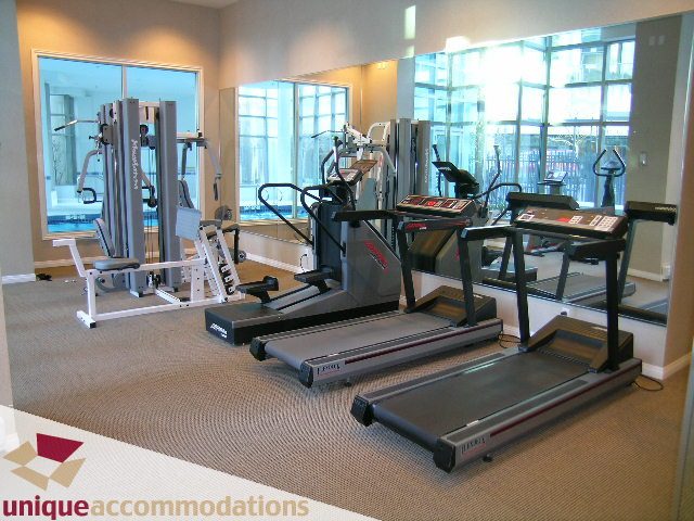 Spacious gym with treadmills and weight machines, large windows offering city views. - 3101 - 1328 W. Pender Street, Vancouver Downtown