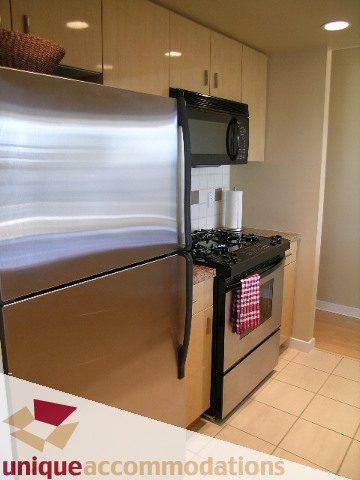Bright kitchen with stainless steel appliances, tiled backsplash, and hardwood floors. - 3101 - 1033 Marinaside Crescent, Vancouver Downtown