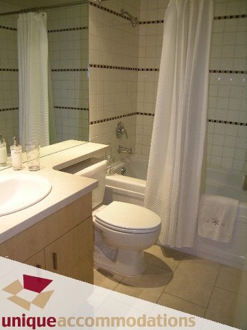 Furnished bathroom with white tiles, modern sink, and shower curtain. - 3101 - 1033 Marinaside Crescent, Vancouver Downtown