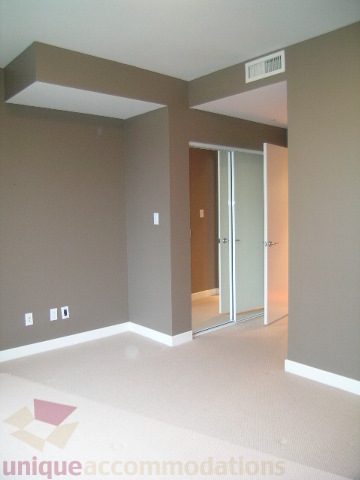 Furnished living room with modern design, neutral walls, and sliding glass doors leading to another room.