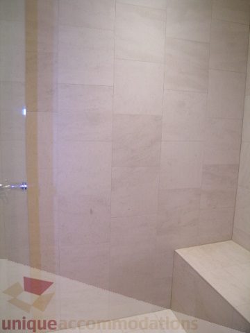Bathroom with marble walls and a corner bench. - 2101 - 1281 West Cordova Street, Vancouver Downtown
