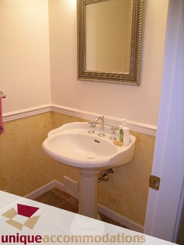 Bathroom with yellow walls, white sink, and decorative mirror. - 1416 Chartwell Drive, West Vancouver