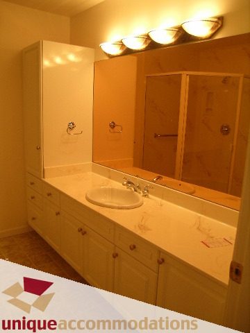 Spacious bathroom with light wood cabinets and a large vanity mirror. - 1416 Chartwell Drive, West Vancouver