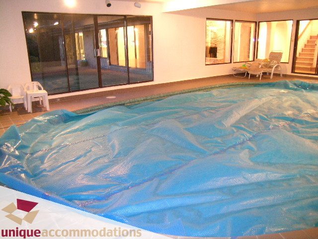Covered indoor pool with patio doors leading outside. - 1416 Chartwell Drive, West Vancouver