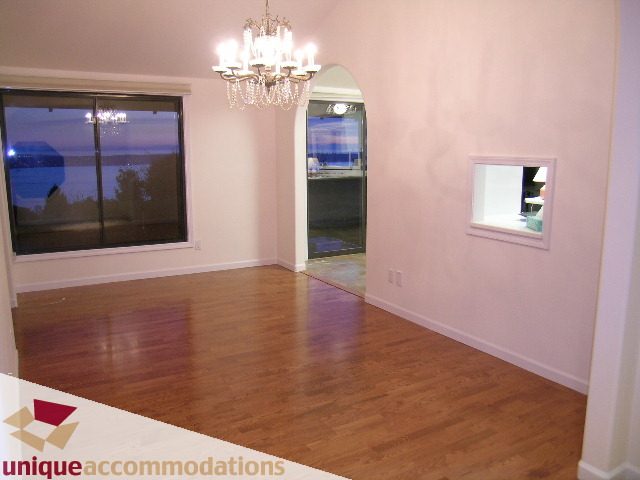 Bright living room with hardwood floors and a large window offering a city view. - 1416 Chartwell Drive, West Vancouver