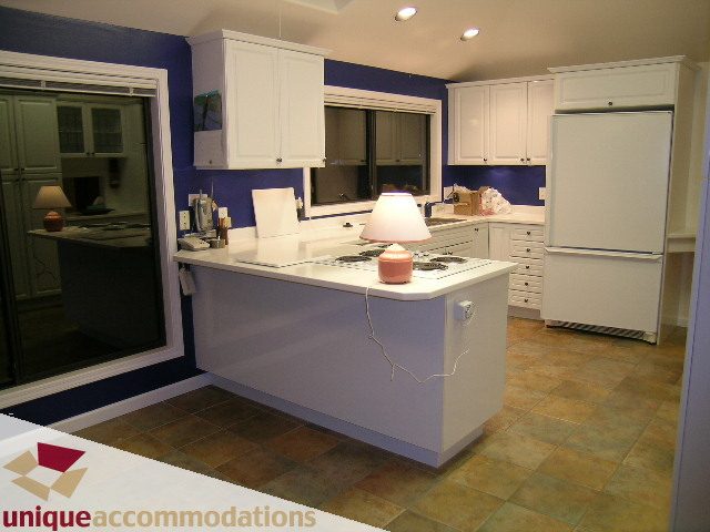 Bright kitchen with white cabinets, blue walls, and tiled floor. - 1416 Chartwell Drive, West Vancouver