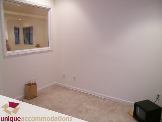 Living room with carpet, small TV, and minimal decor. - 1416 Chartwell Drive, West Vancouver