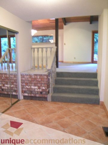 Living room with tiled floor, wooden beams, and large windows. - 4655 Clovelly Walk, West Vancouver