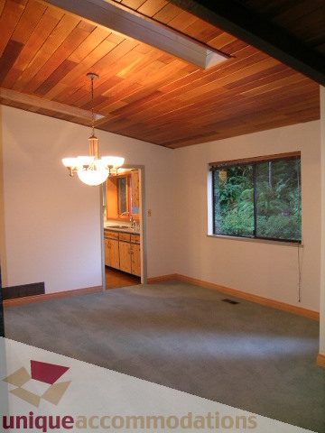 Living room with hardwood ceiling, large windows, and carpeted floors. - 4655 Clovelly Walk, West Vancouver