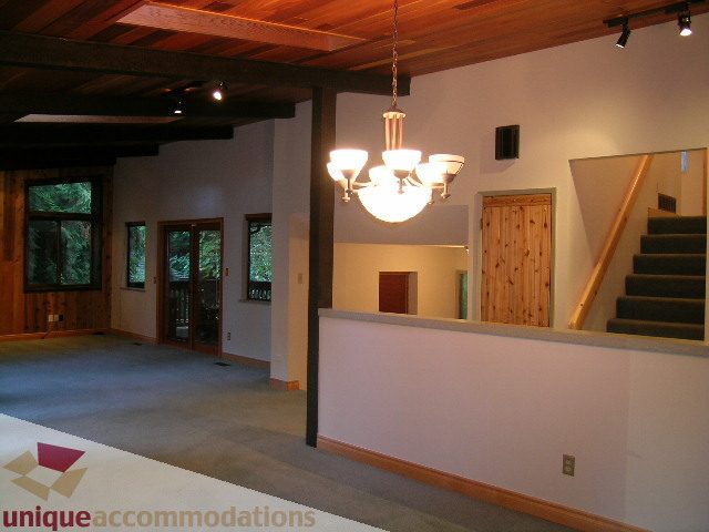 Open-concept living area with exposed beams, modern chandelier, and access to a balcony. - 4655 Clovelly Walk, West Vancouver