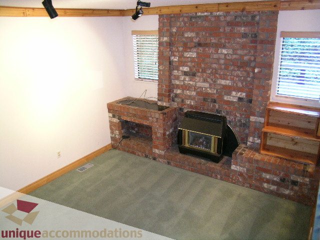Living room with exposed brick fireplace and carpeted floor. - 4655 Clovelly Walk, West Vancouver