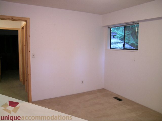 Empty bedroom with carpeted floor and small window view. - 4655 Clovelly Walk, West Vancouver