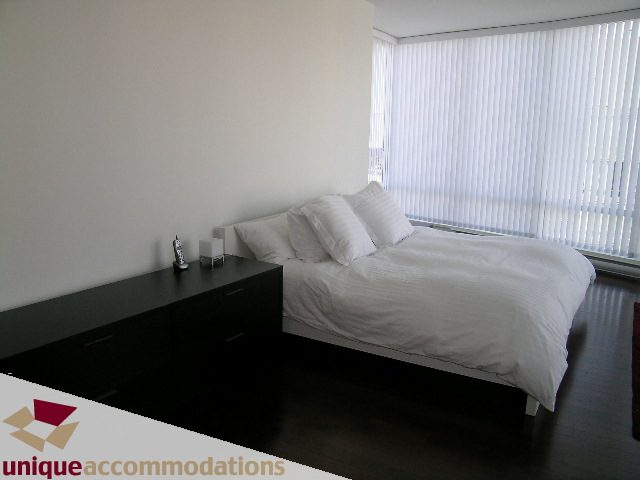 Furnished bedroom with dark wood floors and large window with blinds. - 3801 - 1438 Richards Street, Vancouver Downtown