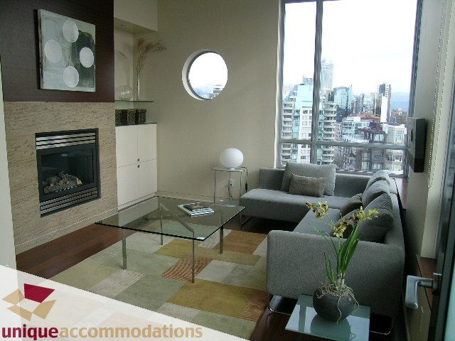 Bright living room with modern furniture, city view, and a circular window. - 2901 - 1005 Beach Avenue, Vancouver Downtown
