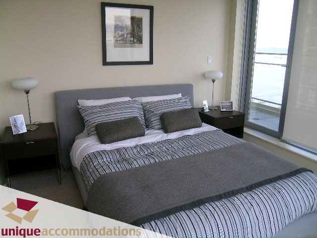 Spacious bedroom with large windows offering a city view, neatly made beds, and modern decor. - 2901 - 1005 Beach Avenue, Vancouver Downtown
