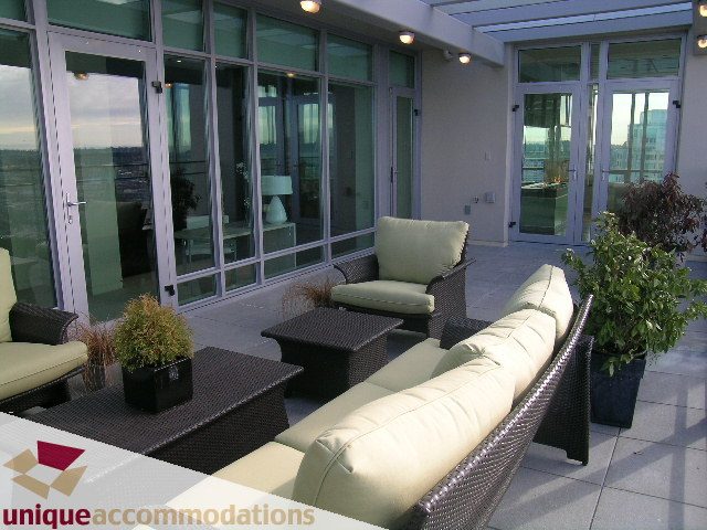 Furnished rooftop patio with wicker furniture, city view, and modern decor. - 2901 - 1005 Beach Avenue, Vancouver Downtown