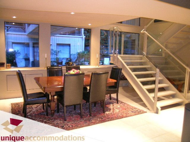 Furnished dining area with modern glass staircase and hardwood floors. - 2 Strachan Point Road, West Vancouver