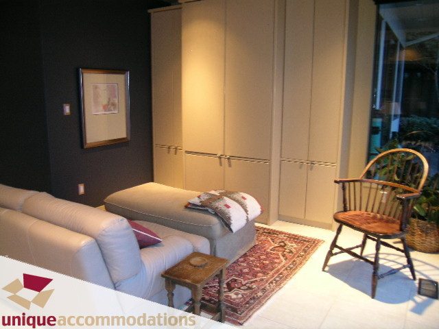 Furnished living room with white couch, patterned rug, and wooden furniture. - 2 Strachan Point Road, West Vancouver