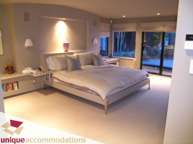 Spacious living room with curved wall, large windows, and cozy seating. - 2 Strachan Point Road, West Vancouver