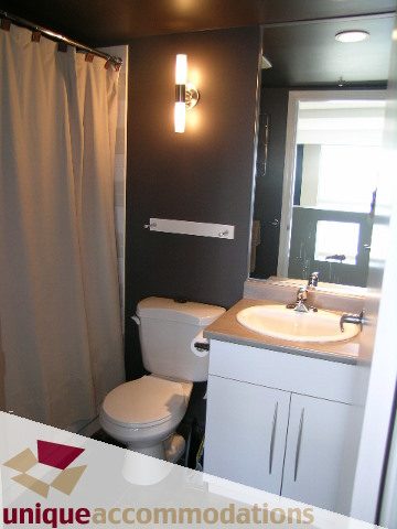 Bright bathroom with white cabinets and modern sink, featuring a black wall and a wall-mounted light fixture.