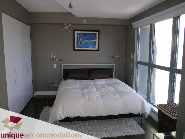 Furnished 1-bedroom loft with modern decor, large windows, and a cozy bed setup. - 2001 - 1238 Richards Street, Vancouver Downtown