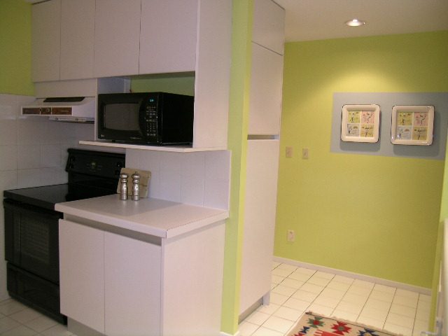 Bright kitchen with white cabinets, green walls, and a black microwave. - Guest House - 440 Stevens Drive, West Vancouver