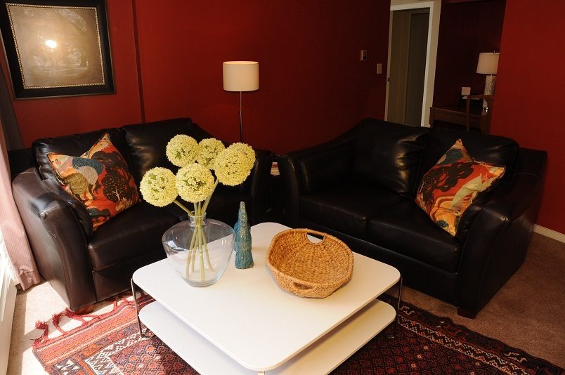 Living room with black leather sofas, white coffee table, and red walls. - Guest House - 440 Stevens Drive, West Vancouver