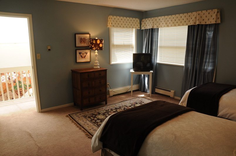 Bright bedroom with wooden dresser, patterned rug, and window with blinds. - Guest House - 440 Stevens Drive, West Vancouver