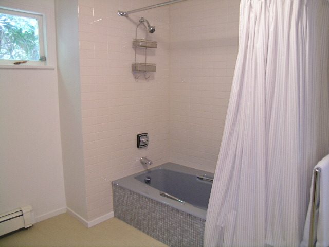 Guest bathroom with tiled walls, modern shower, and bathtub. - Guest House - 440 Stevens Drive, West Vancouver
