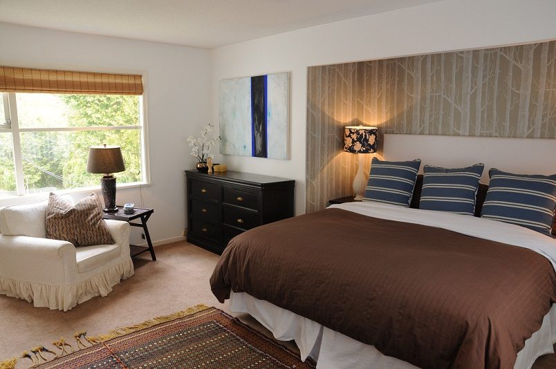 Spacious bedroom with a king-sized bed, brown bedding, and a black dresser. - Guest House - 440 Stevens Drive, West Vancouver