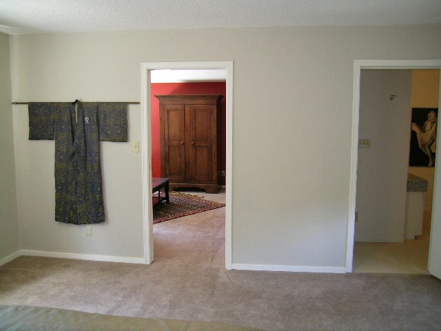 Living room with beige carpet, open door leading to another room, and hanging fabric decoration. - Guest House - 440 Stevens Drive, West Vancouver