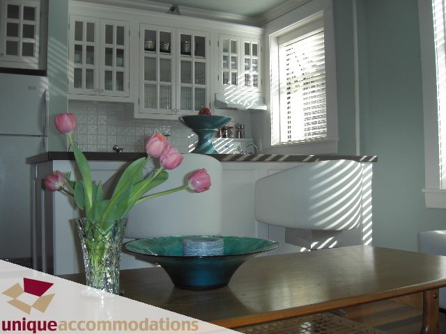 Bright kitchen with white cabinets, teal accents, and a vase of tulips on the counter. - 45 - 777 Burrard Street, Vancouver Downtown
