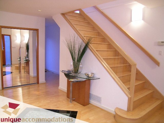Bright living room with wooden staircase, hardwood floors, and modern decor. - 3967 West Broadway, Vancouver West Side