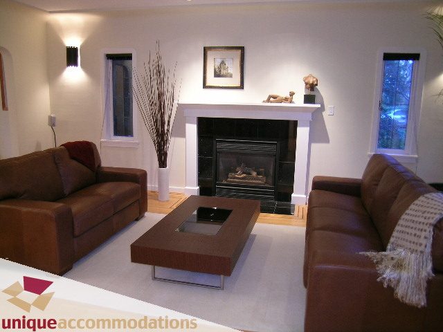 Spacious living room with brown leather sofas, fireplace, and modern decor. - 3967 West Broadway, Vancouver West Side