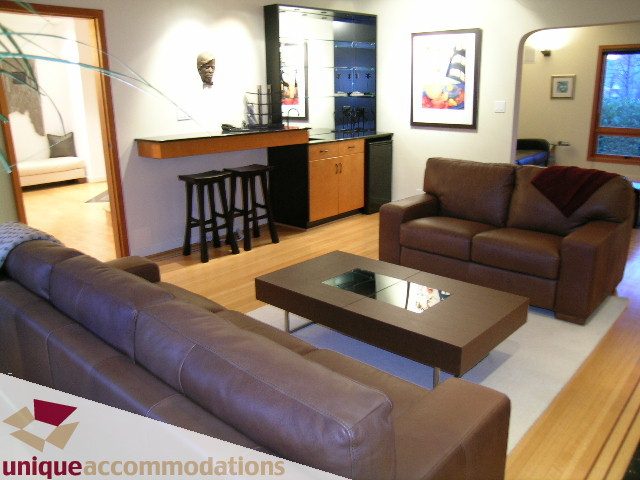 Furnished living room with leather couches, hardwood floors, and a bar area. - 3967 West Broadway, Vancouver West Side