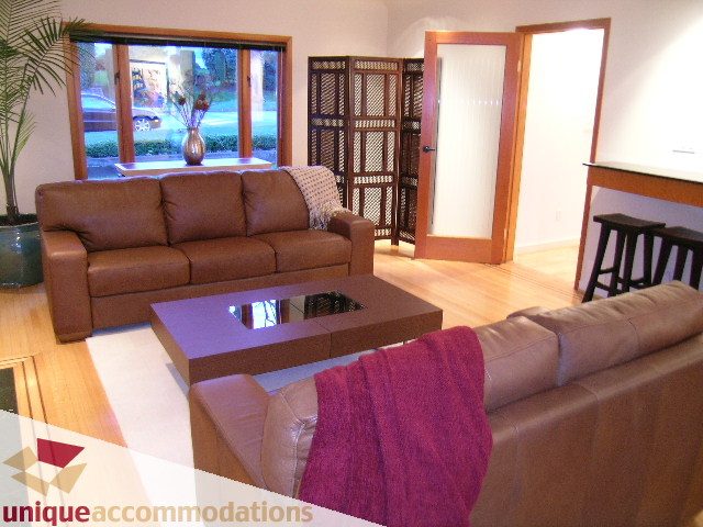 Furnished living room with hardwood floors, large windows, and a cozy sofa. - 3967 West Broadway, Vancouver West Side