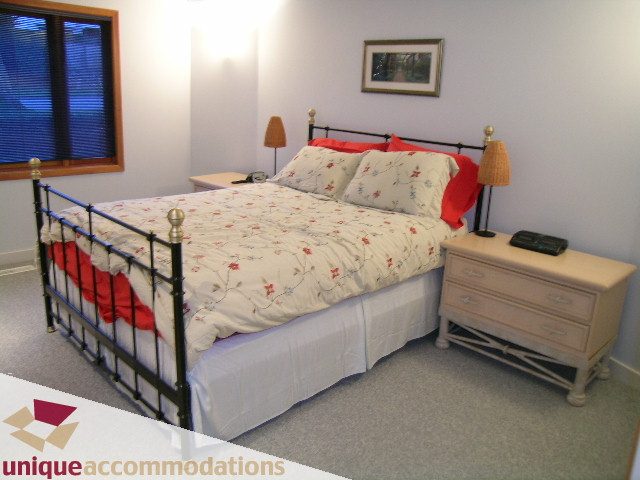 Spacious bedroom with iron bed frame, floral bedding, and nightstands. - 3967 West Broadway, Vancouver West Side