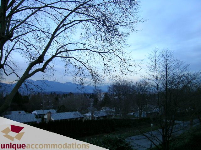 Furnished living room with city view and bare trees. - 3967 West Broadway, Vancouver West Side