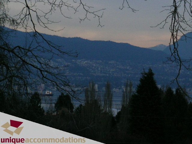 Furnished living room with city view and mountain backdrop. - 3967 West Broadway, Vancouver West Side