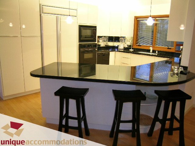 Bright kitchen with black countertops, white cabinets, and hardwood floors. - 3967 West Broadway, Vancouver West Side