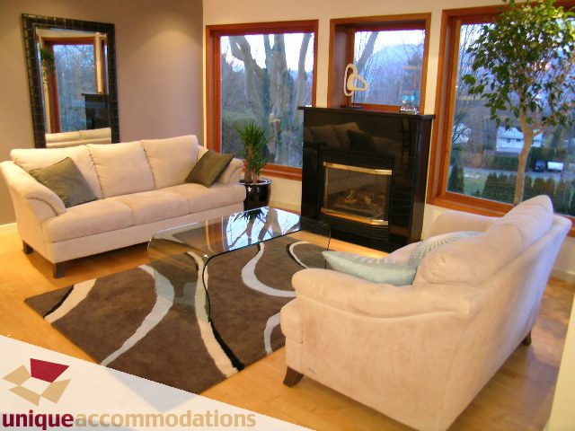 Spacious living room with large windows, modern furniture, and a fireplace. - 3967 West Broadway, Vancouver West Side