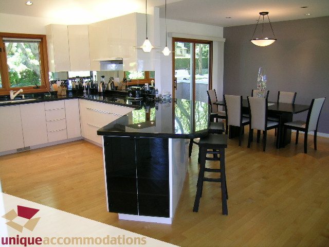 Bright kitchen with white cabinets, black countertops, and hardwood floors. - 3967 West Broadway, Vancouver West Side
