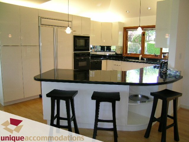 Bright kitchen with white cabinets, black countertops, and hardwood floors. - 3967 West Broadway, Vancouver West Side