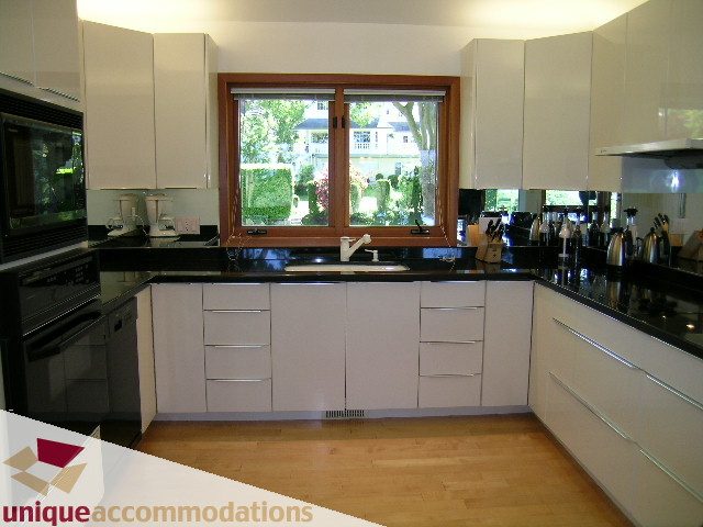 Bright kitchen with modern white cabinets, black countertops, and hardwood floors. - 3967 West Broadway, Vancouver West Side