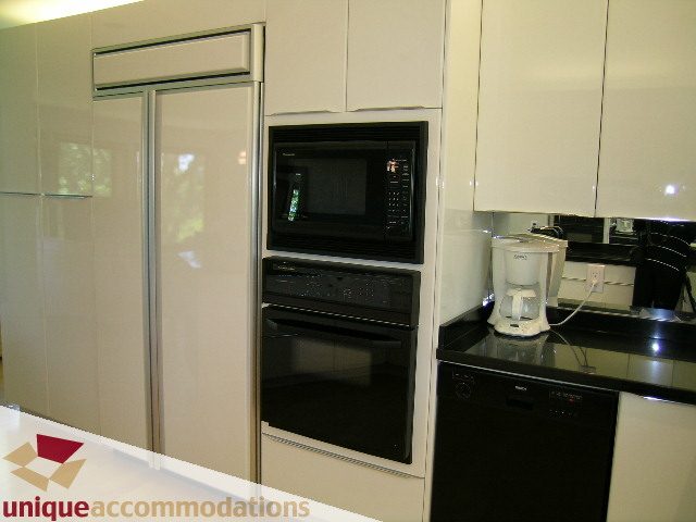 Bright kitchen with modern appliances, white cabinets, and black countertops. - 3967 West Broadway, Vancouver West Side