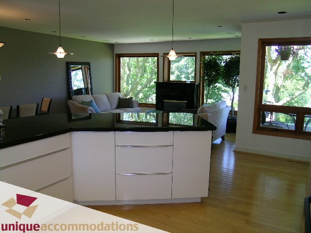 Bright living room with hardwood floors and large windows, showcasing a serene outdoor view. - 3967 West Broadway, Vancouver West Side