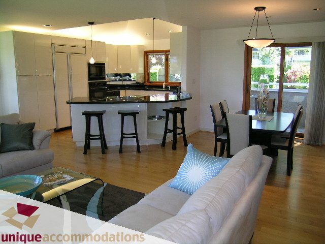Open-concept living space with modern furnishings, hardwood floors, and a kitchen island. - 3967 West Broadway, Vancouver West Side